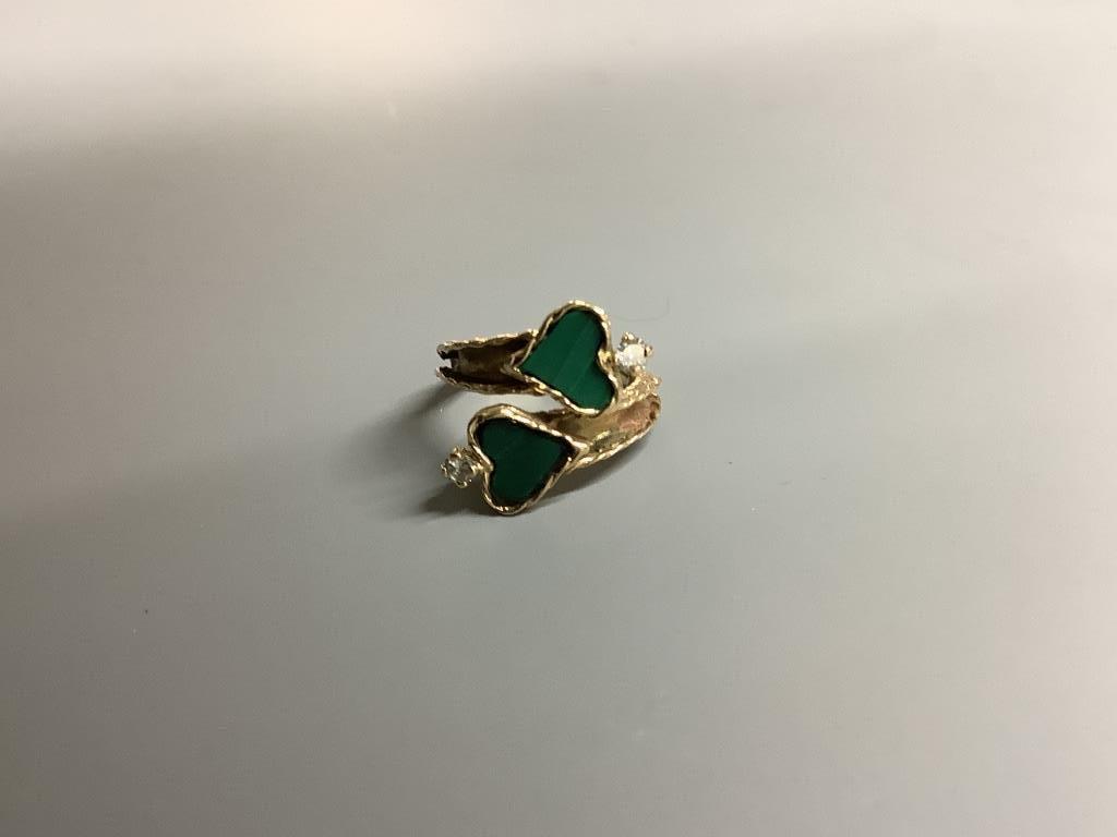 A modern yellow metal, two stone heart shaped malachite and two stone diamond set crossover ring, size F/G, gross 3.9 grams.